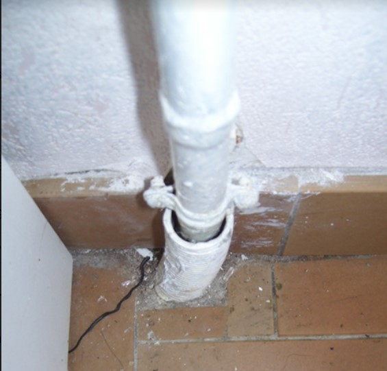 Photo d'un passage de tuyauterie non étanche dans un mur.
